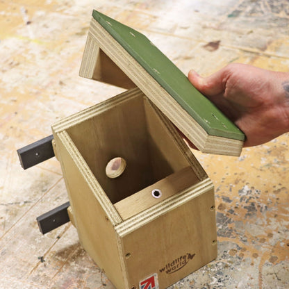 Wooden dormouse box with green top held by a hand on a wooden surface