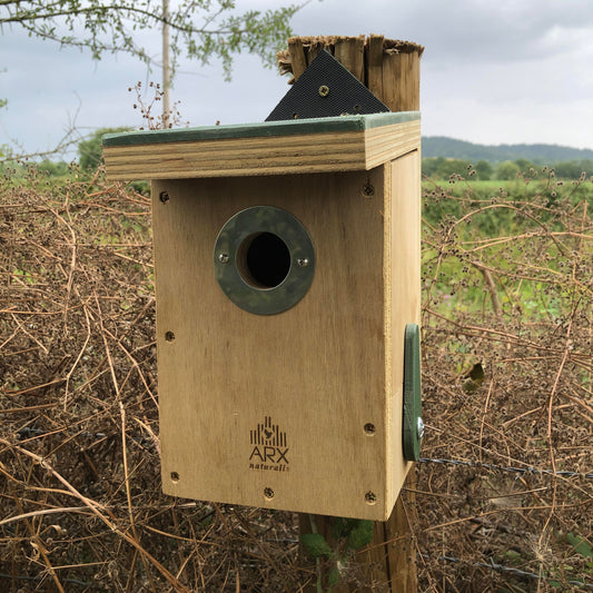 Wooden birdhouse with ARX Naturally logo on a natural background